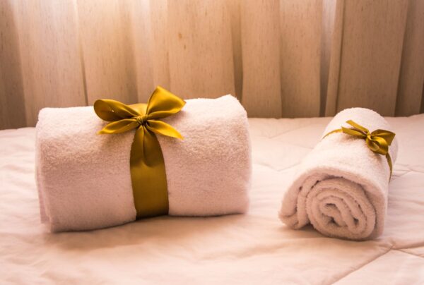 pexels-photo-1304110-1304110 Luxurious white towels adorned with golden ribbons on a bed, creating an elegant and welcoming atmosphere.