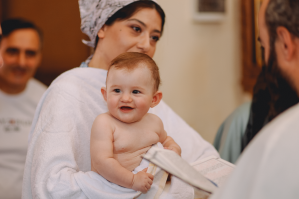 pexels-photo-17942940-17942940 Adorable baby held by a mother during a baptism ceremony in a church setting.