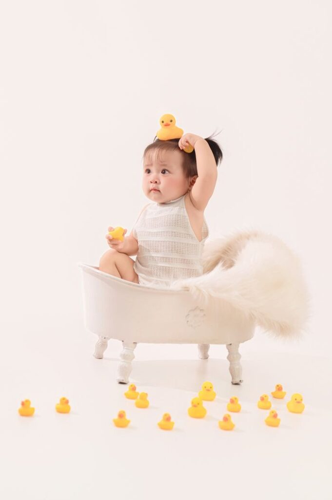 Cute baby in a mini bathtub surrounded by rubber ducks, offering a playful and joyful scene.