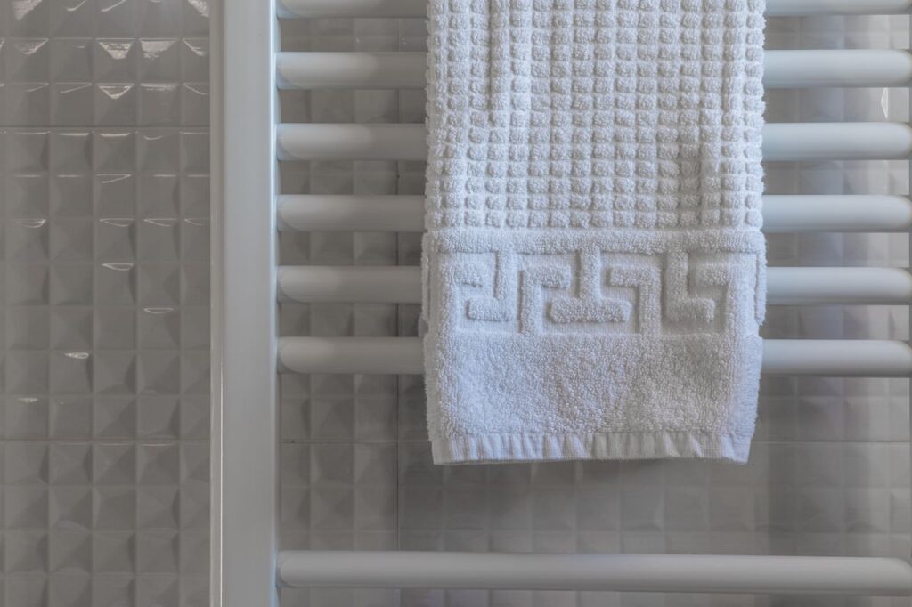 White towel on a radiator in a modern, minimalist bathroom with tiled walls.