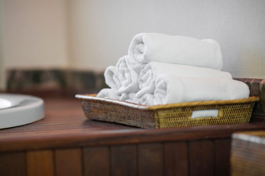 Rolled white towels neatly placed in a woven basket, perfect for spa or bathroom decor.