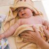 pexels-photo-4668938-4668938 Cute newborn baby wrapped in a soft towel, smiling and feeling cozy indoors.