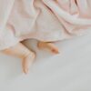 pexels-photo-4964225-4964225 Adorable baby feet peeking out from under a soft pink blanket.
