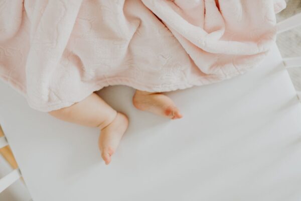 pexels-photo-4964225-4964225 Adorable baby feet peeking out from under a soft pink blanket.