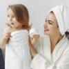 pexels-photo-3985042-3985042 A smiling mother and daughter in bathrobes enjoying a playful moment indoors.