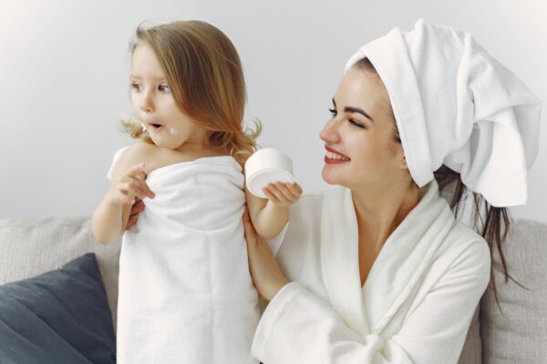 A smiling mother and daughter in bathrobes enjoying a playful moment indoors.